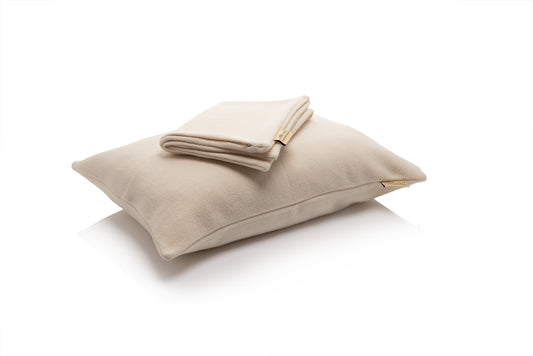 Beige pillow with folded beige merino wool pillow case on a white background
