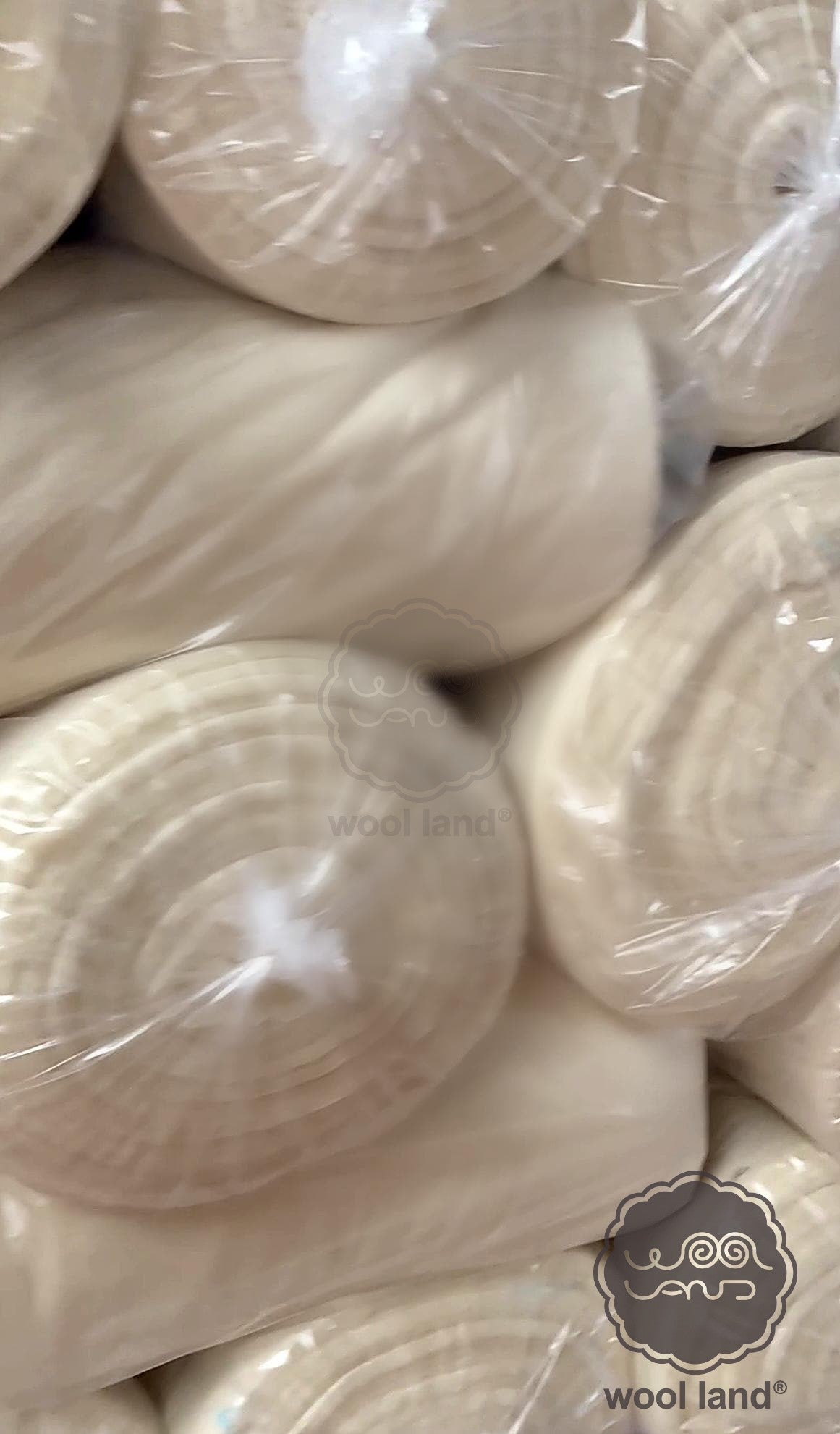 Close-up of merino wool rolls with 'wool land' branding.