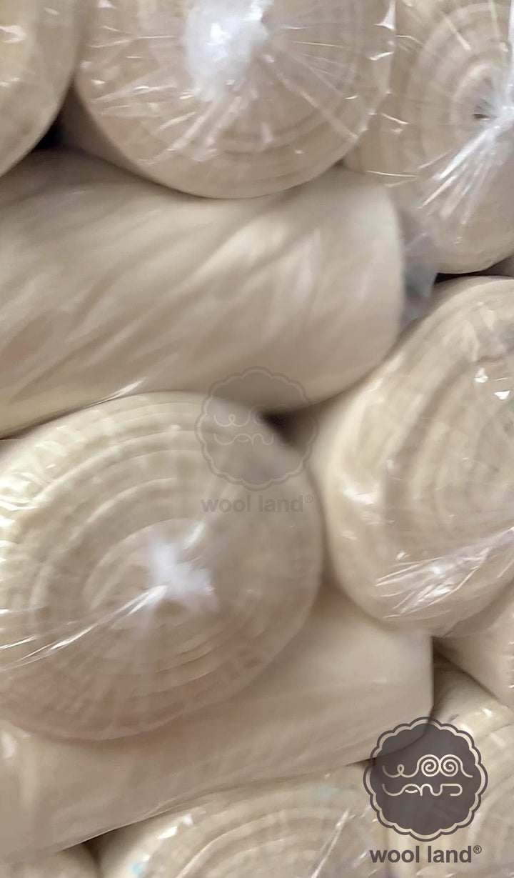 Close-up of merino wool rolls with 'wool land' branding.