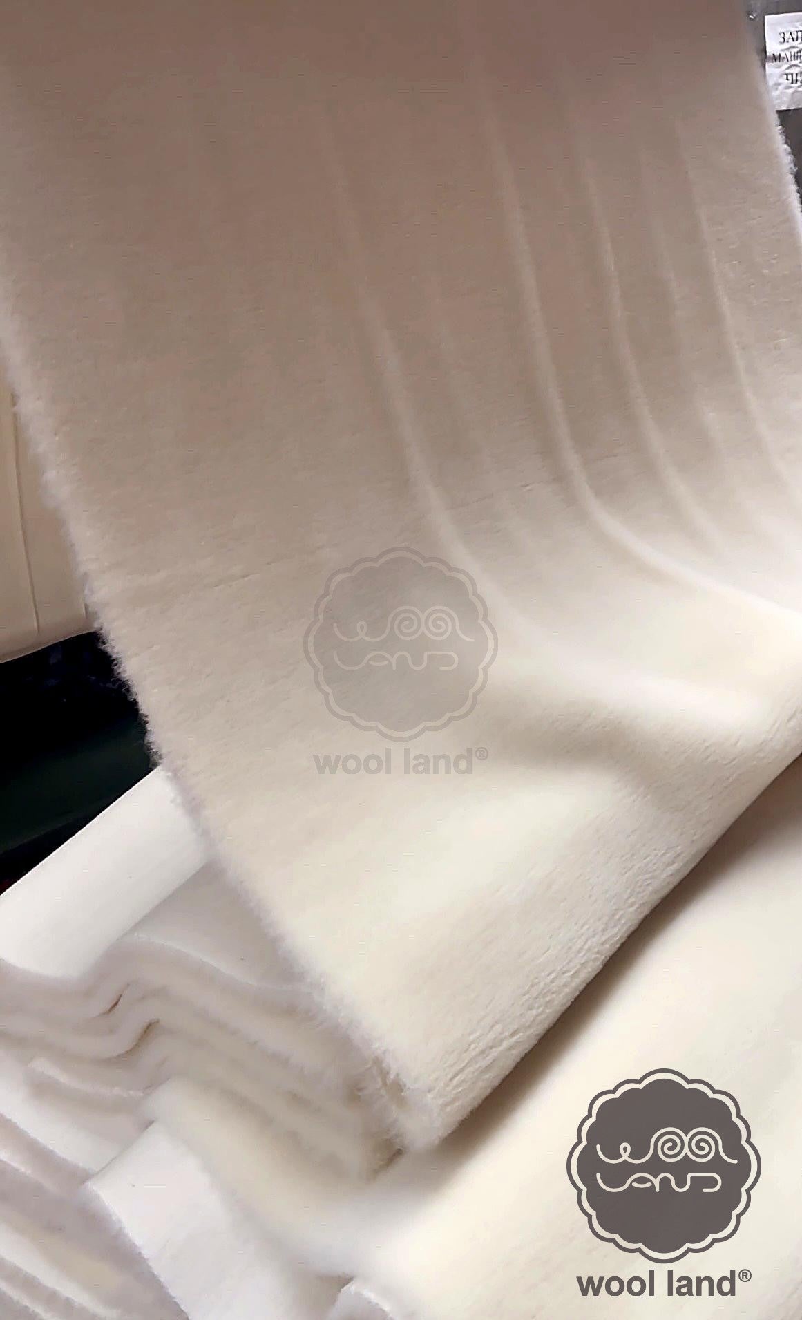Close-up of merino wool fabric with 'wool land' branding