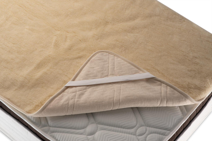 Merino wool  mattress pad on a bed with a white background. Handcrafted by Woolland 