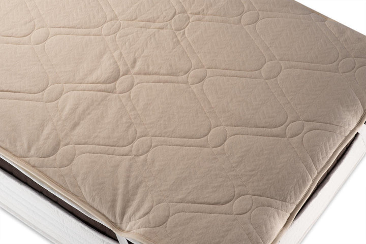 Hemp and organic cotton quilted mattress topper on a bed. Handmade by Woolland 