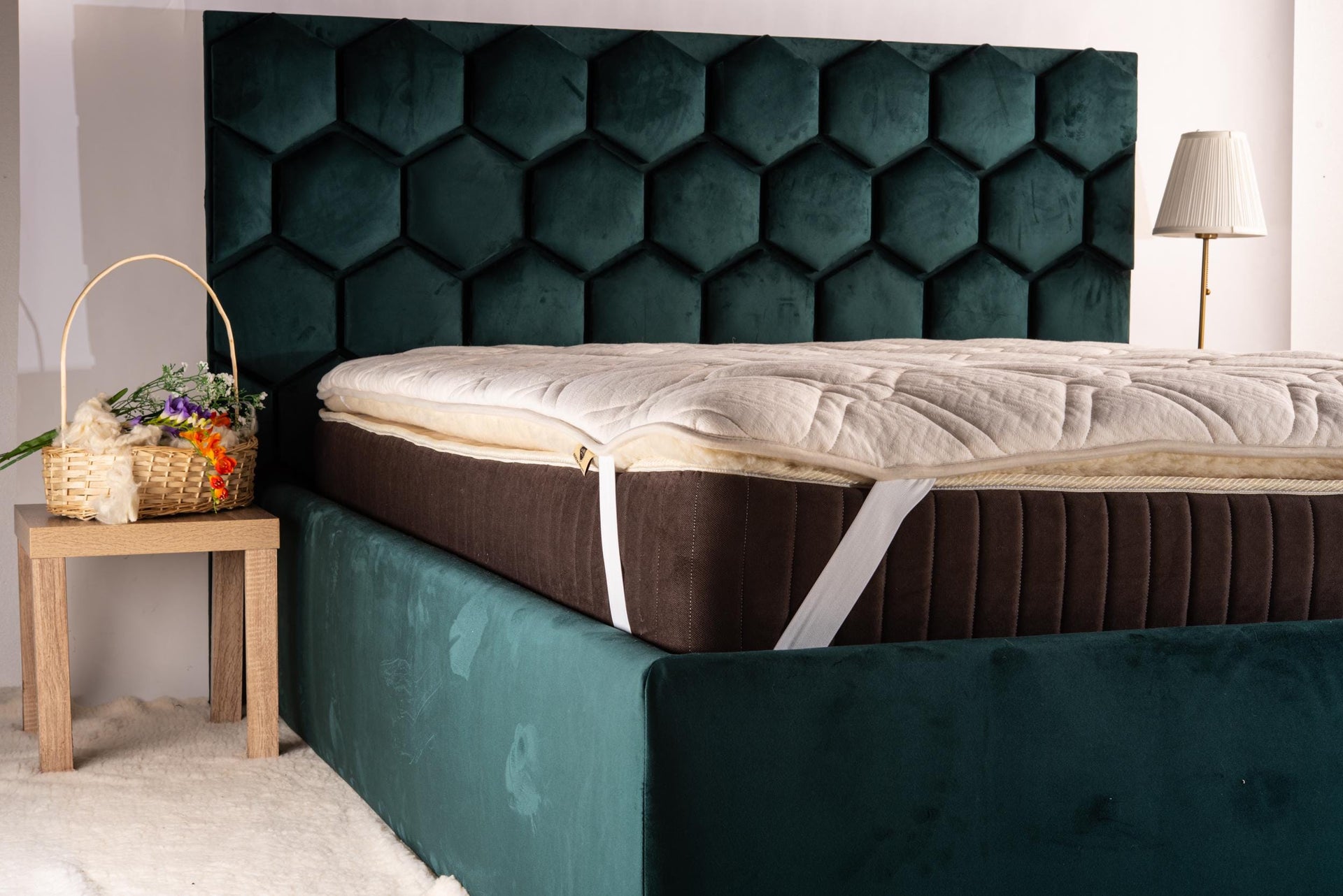 Green upholstered bed with a hemp mattress topper on a wooden floor. Handmade by Woolland