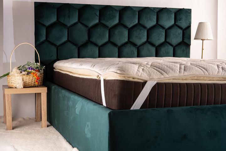 Green upholstered bed with a hemp mattress topper on a wooden floor. Handmade by Woolland