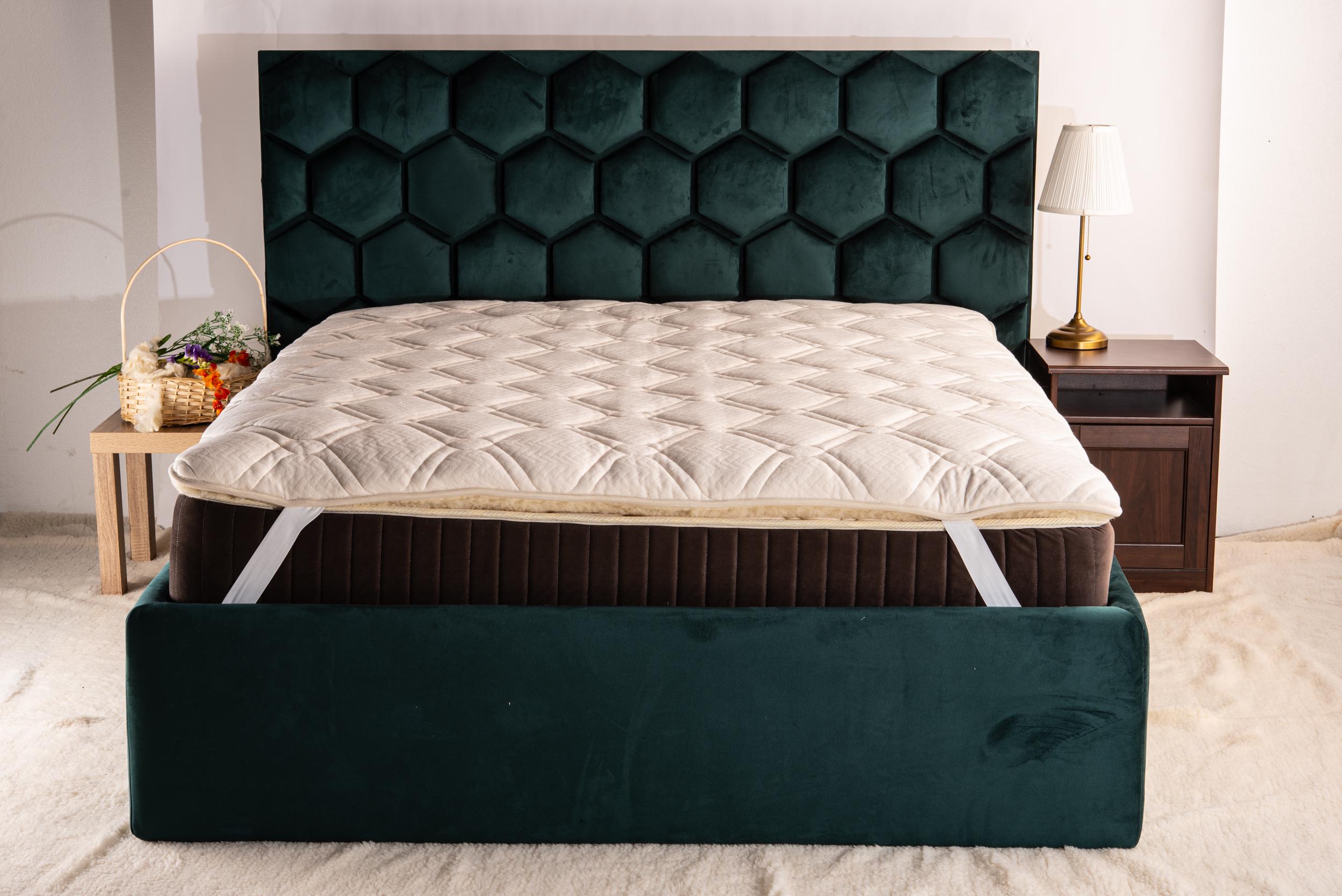 Mattress topper on a green upholstered bed in a bedroom setting. Handmade by  Woolland