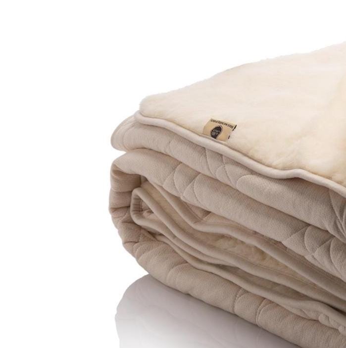 Folded beige merino wool blanket with a brand logo of Woolland on a white background