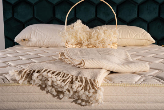 Bed with checkered design merino wool TV blanket and organic pillows on a dark hexagonal patterned wall. Handrafted by Woolland