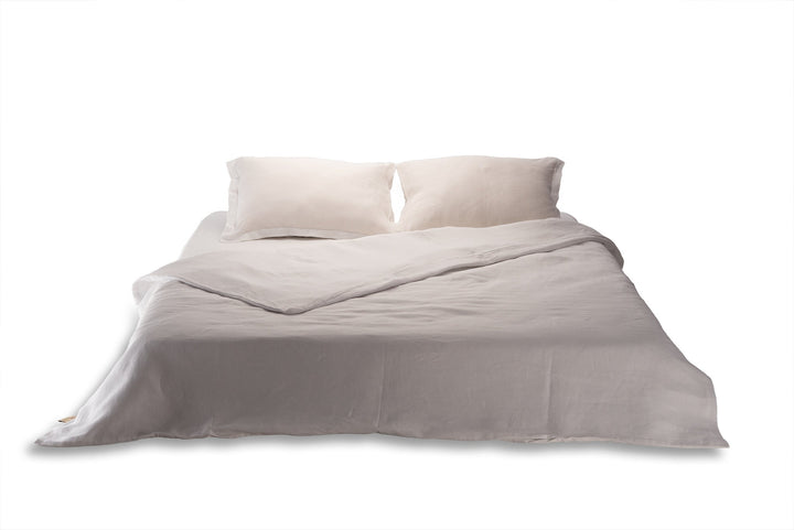 White linen duvet cover and pillows on a bed on white background handcrafted by Woolland