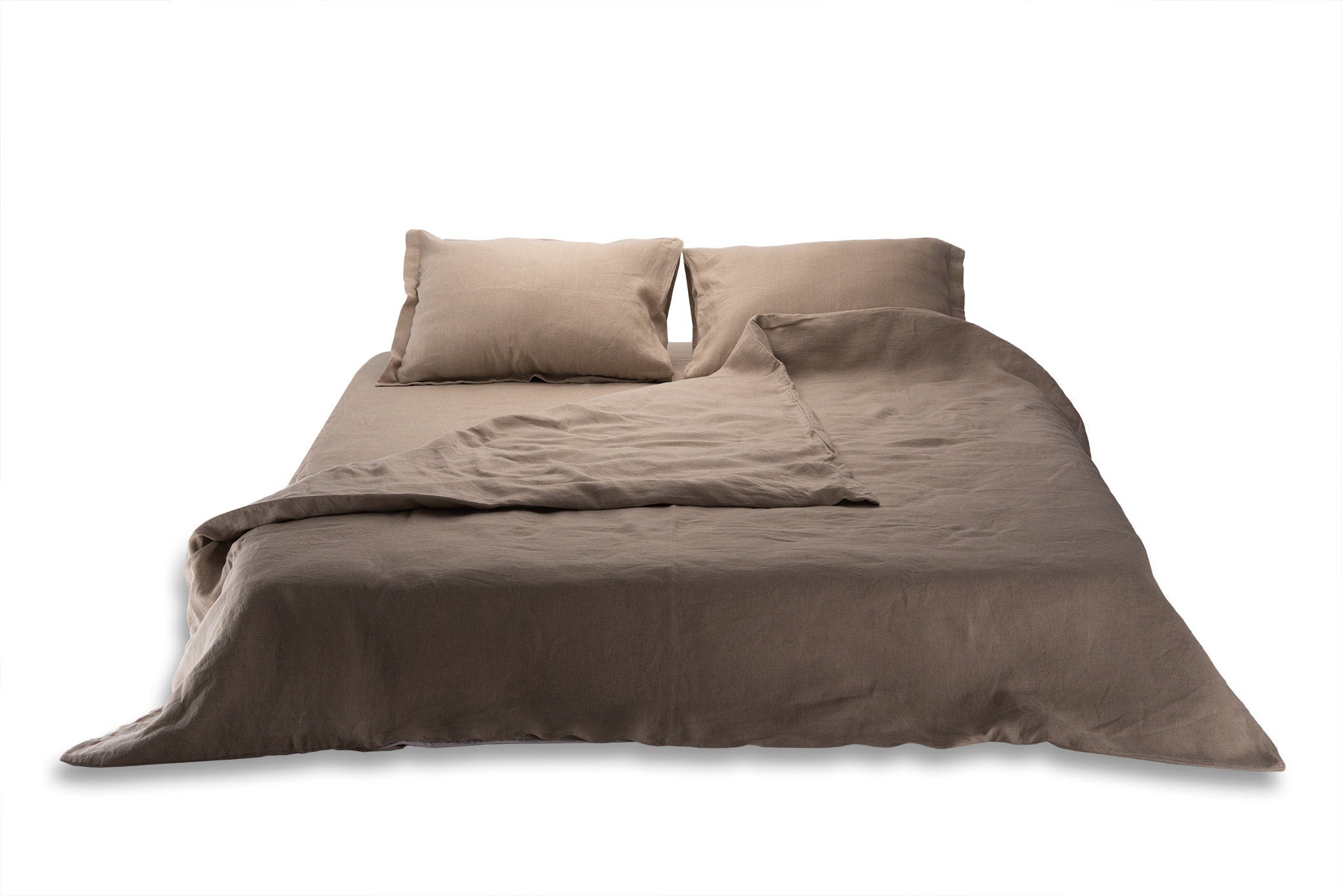 Natural linen bedding set on a bed with pillows on a white background by Woolland