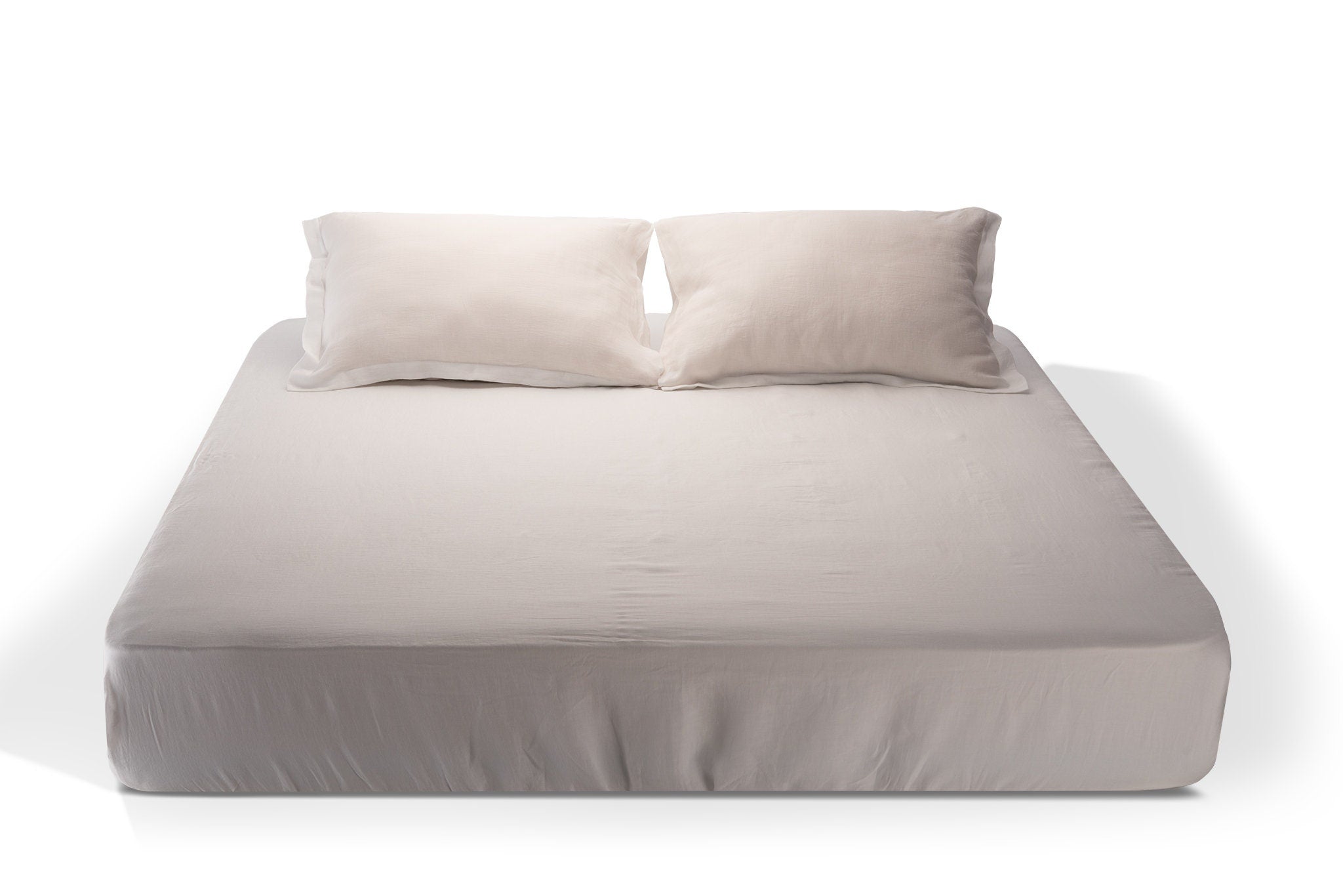 Pure white linen fitted sheet and two oxford designed pillow cases on a bed handmade by Woolland