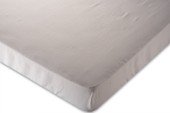 corner photo of white pure linen fitted sheet on a white background. Handmade by the Woolland