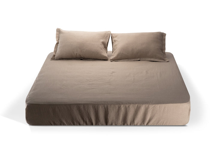 Natural color linen fitted sheet with matching pillows on a white background. Made by the Woolland