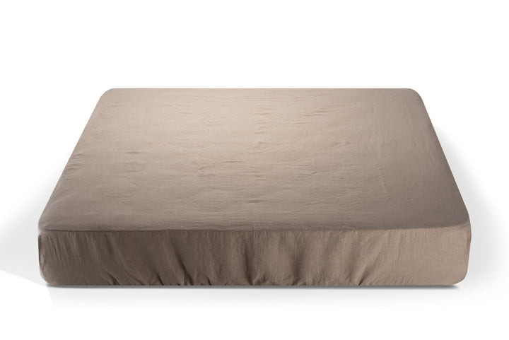 Natural color linen fitted sheet on a mattress on a white background. Made by Woolland
