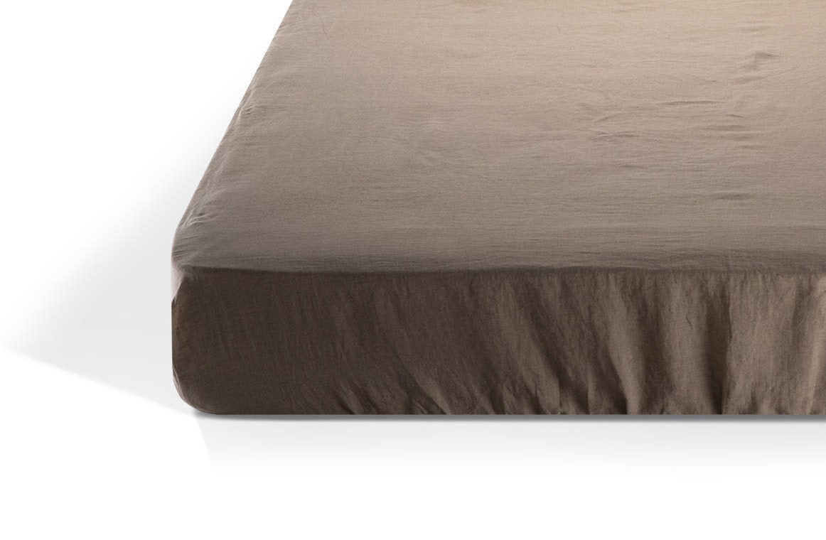 Natural linen fitted sheet on a mattress against a white background