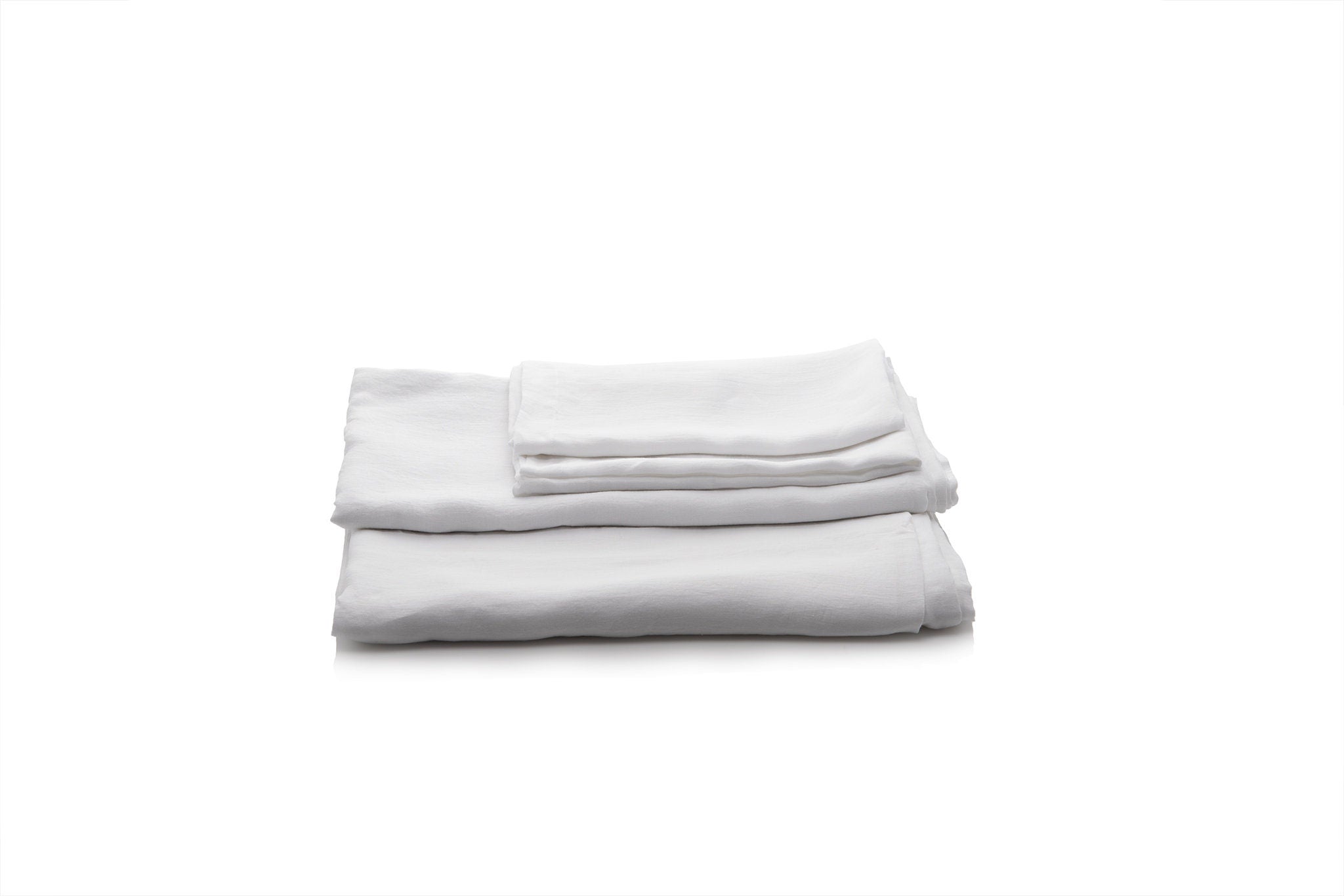 Folded white linen bed sheets on a white background by Woolland