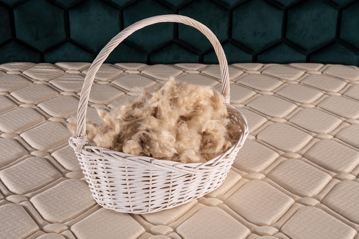 Basket filled with raw kapok fibers on a textured surface with a dark geometric patterned background