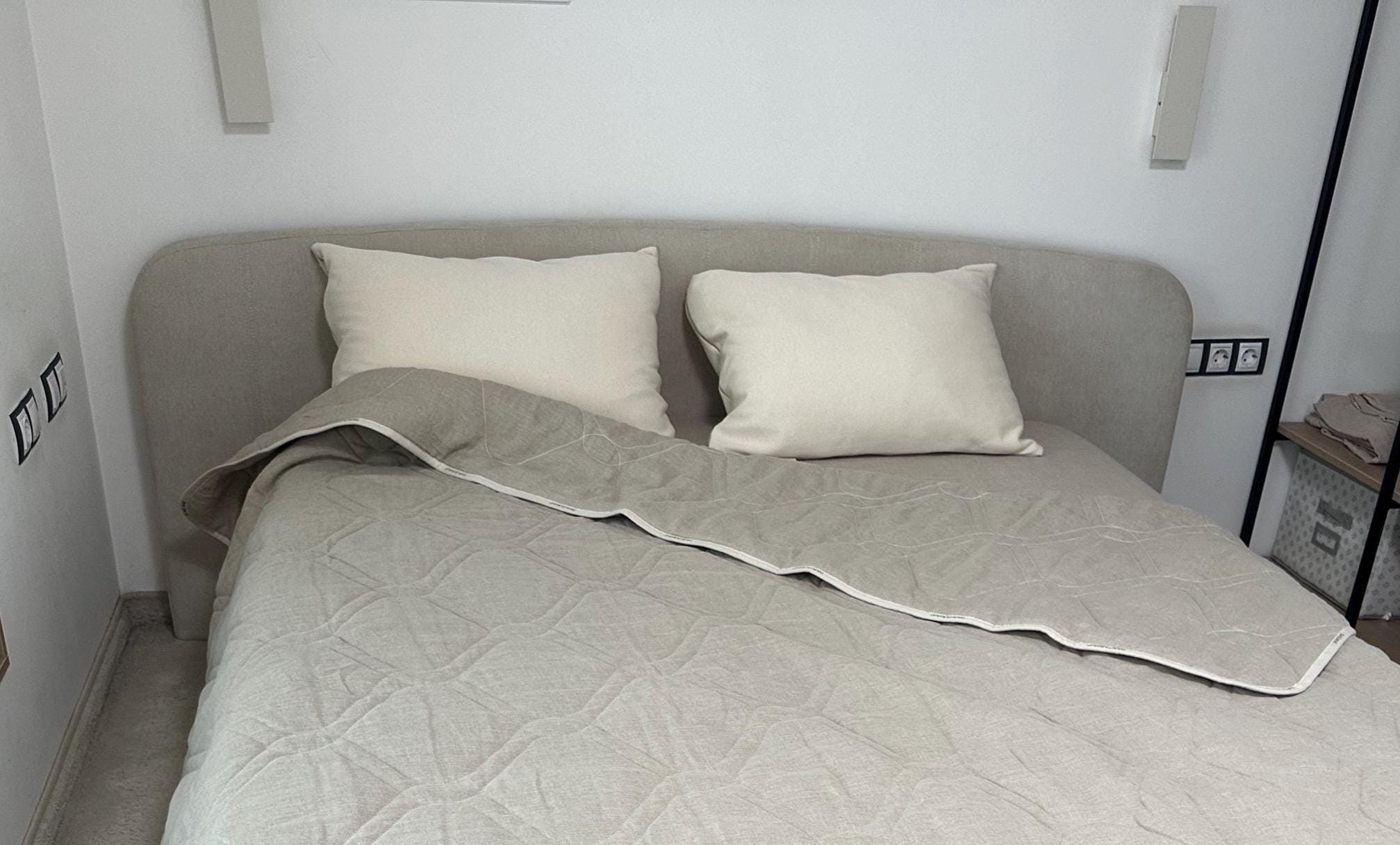 Bed with beige bedding and organic cotton bed pillows in a minimalistic room.