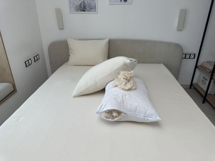 Bed with organic cotton and kapok filling pillows and a decorative item in a room setting handcrafted by the Woolland
