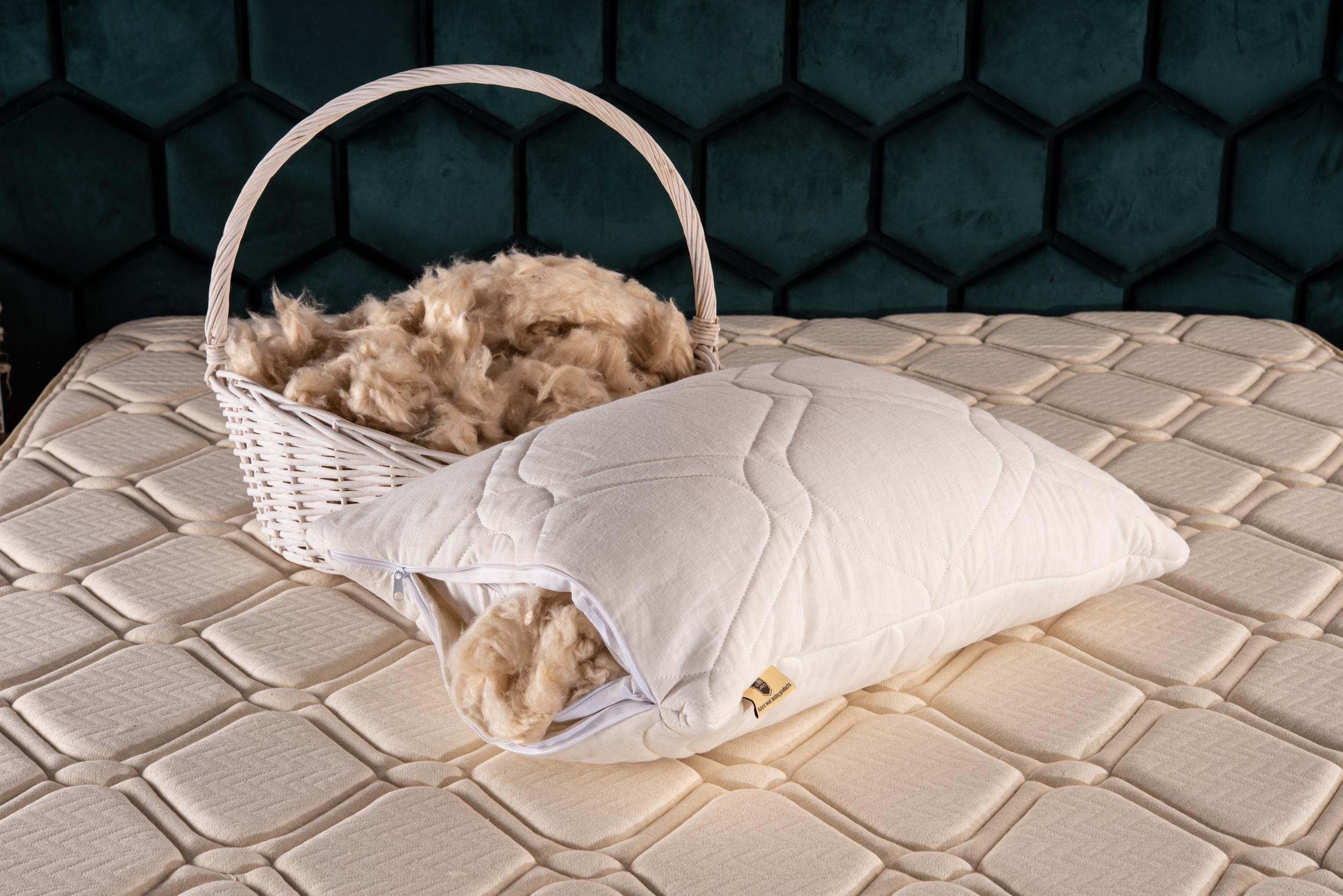 Basket with kapok and quilted natural pillow on a mattress against a dark hexagonal patterned wall by Woolland