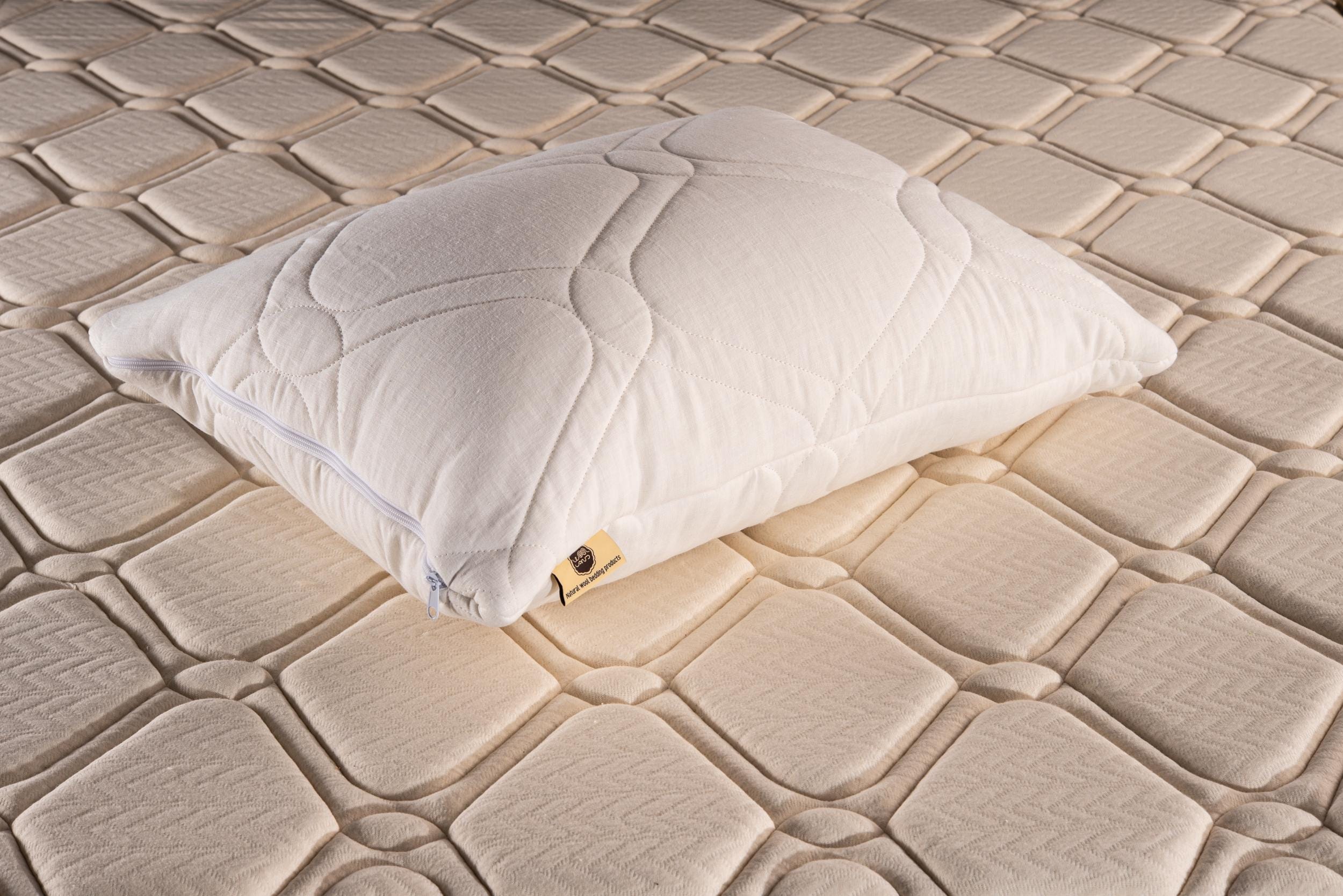 White linen quilted pillow on a textured beige mattress by Woolland