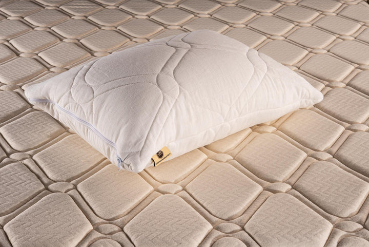 White linen quilted pillow on a textured beige mattress by Woolland