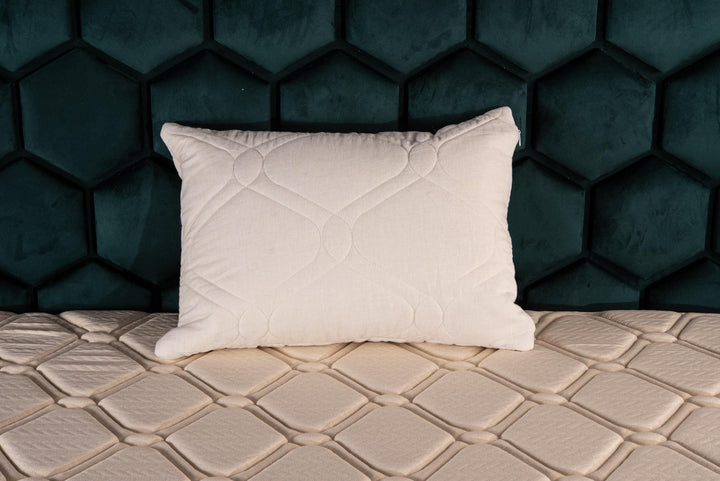 White linen cover and kapok filled pillow on a textured surface with a dark hexagonal patterned wall in the background by Woolland