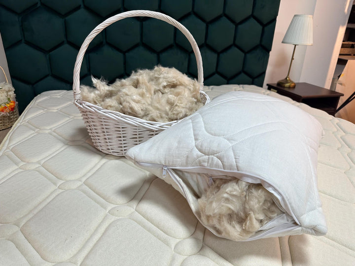 Basket and pillow filled with  kapok natural fibers on a bed against a hexagonal patterned wall. Handmade by Woolland