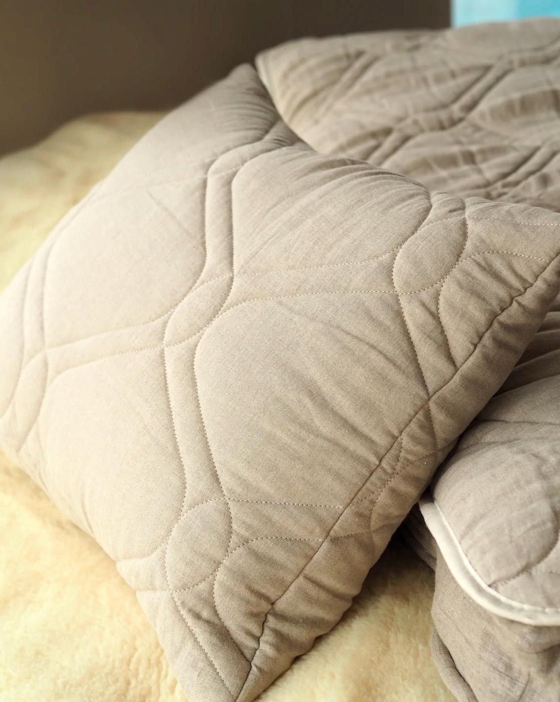 Close-up of a beige quilted pure linen pillow on a bed handcrafted by the Woolland