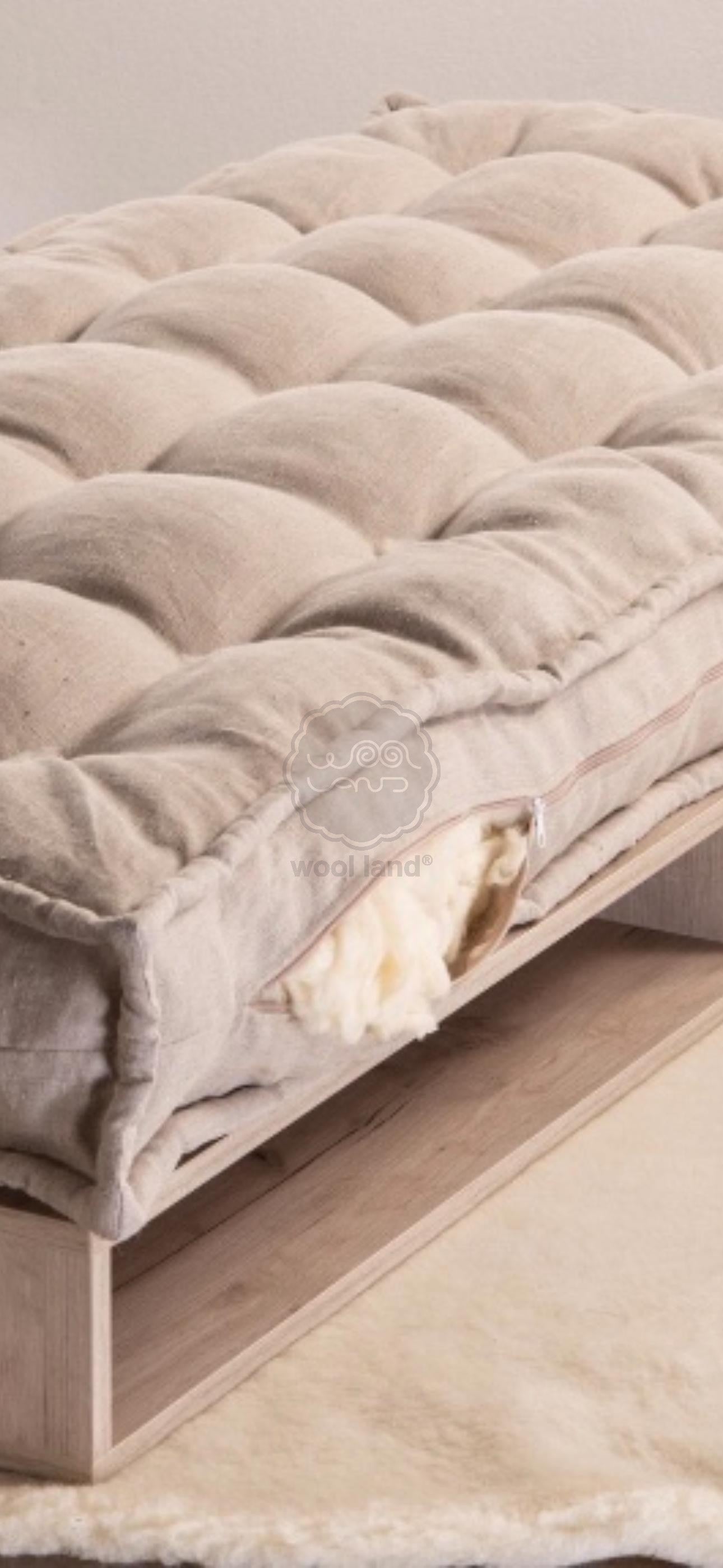 Linen covered tufted cushion with raw wool stuffing on a wooden bench with a soft texture. Handmade by Woolland