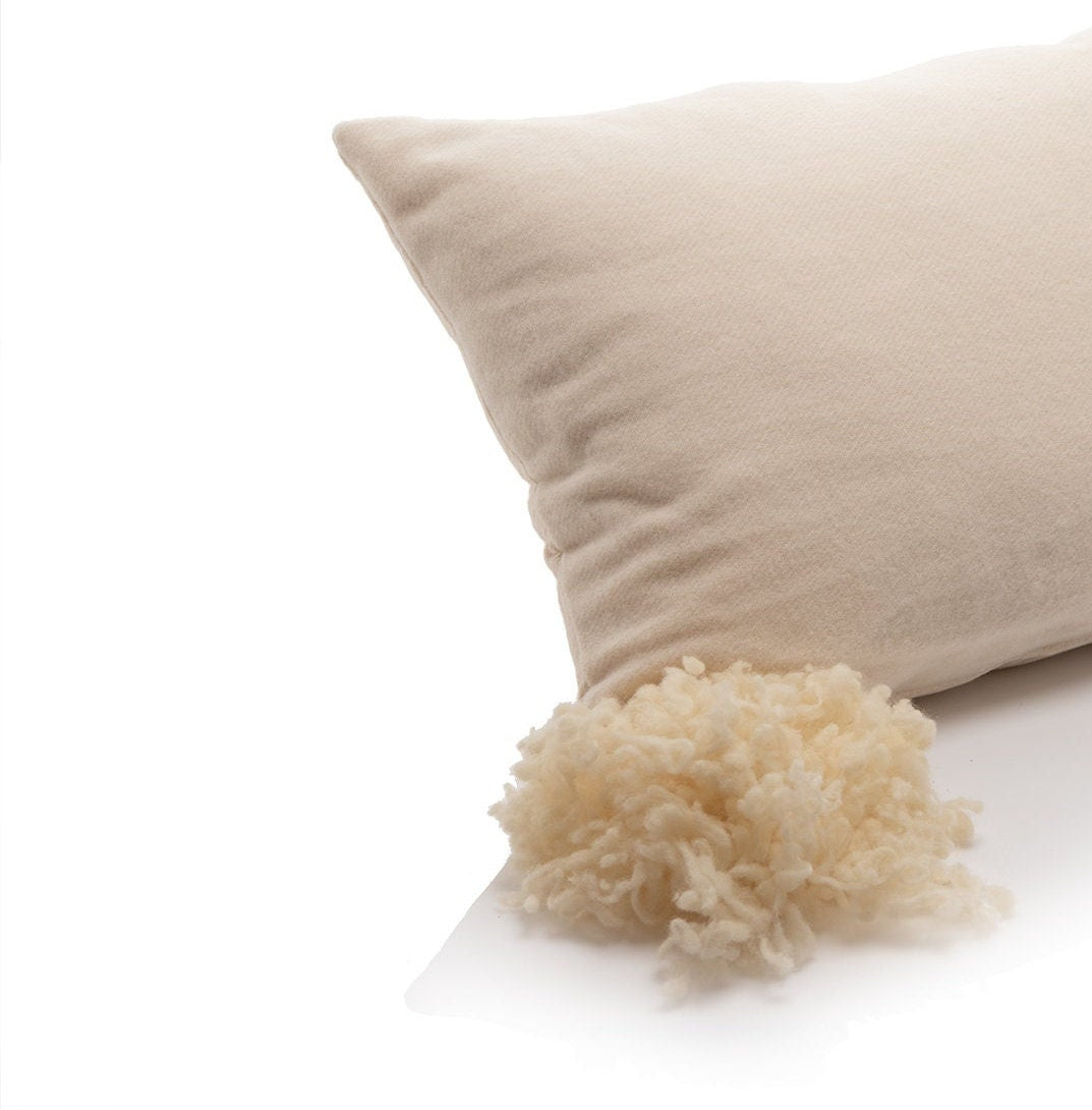 Merino wool pillow with raw wool pom-pom on a white background by Woolland
