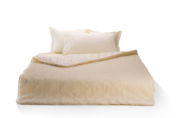 Merino wool and cotton sateen blanket on a bed . Handmade by Woolland.