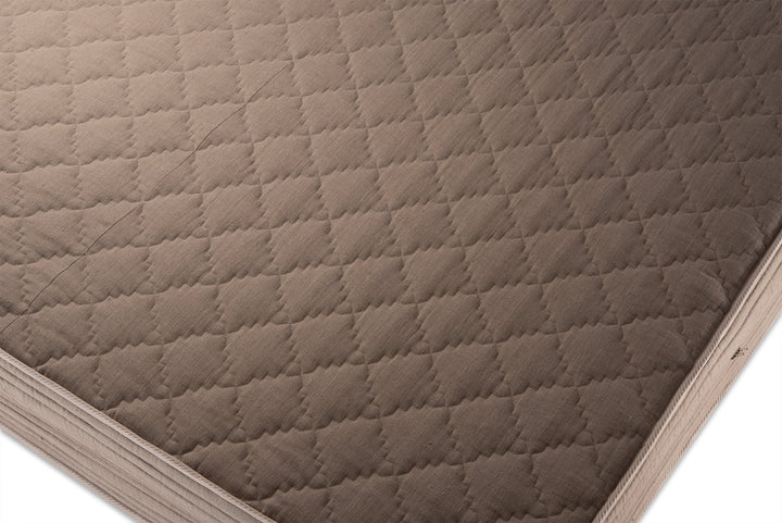 Quilted linen side of a mattress cover  with diamond pattern on a white background