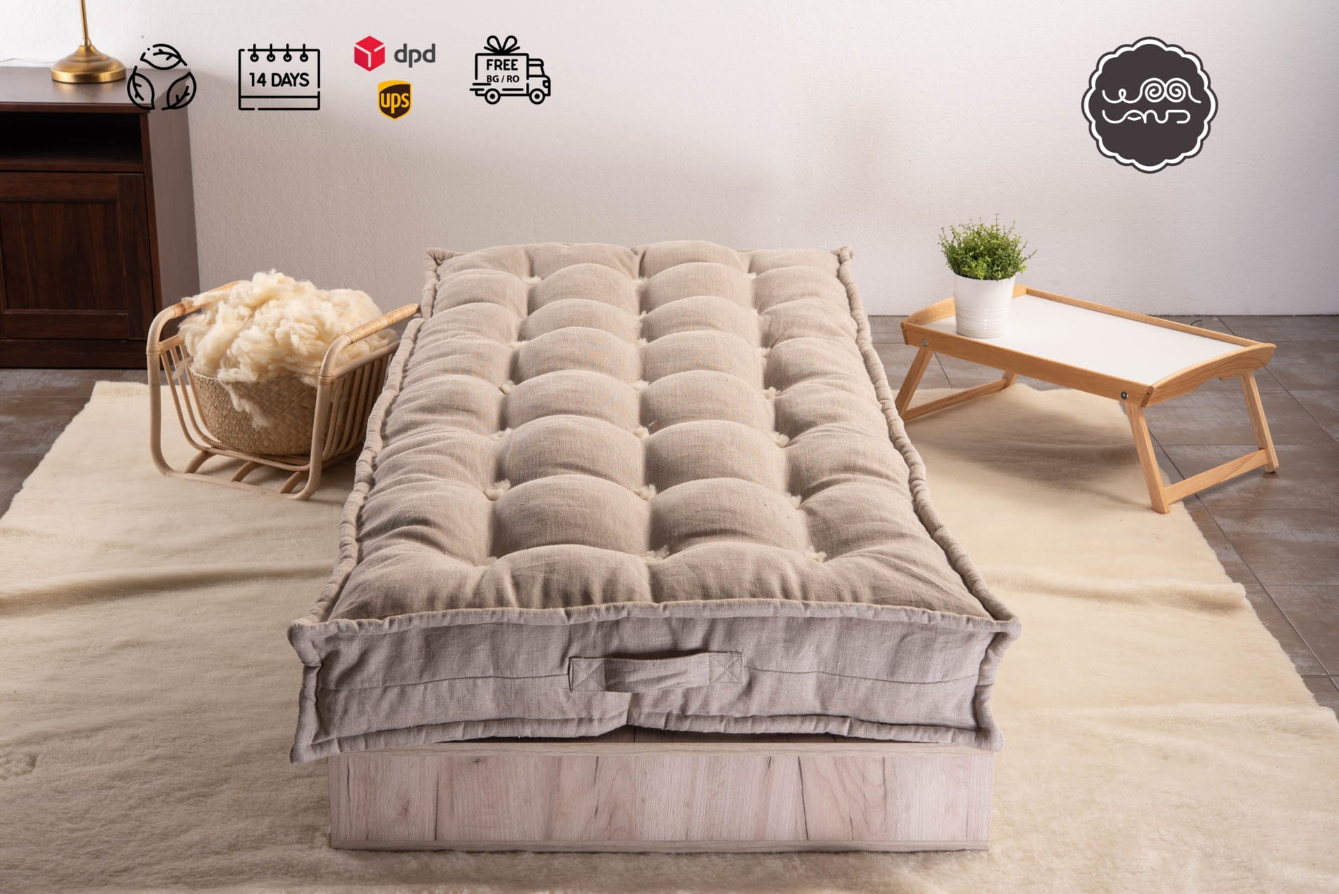 A mattress topped with merino wool and linen, displayed on a bed frame with a linen cover, set against a neutral background with a wicker chair and a small wooden side table in the background.
