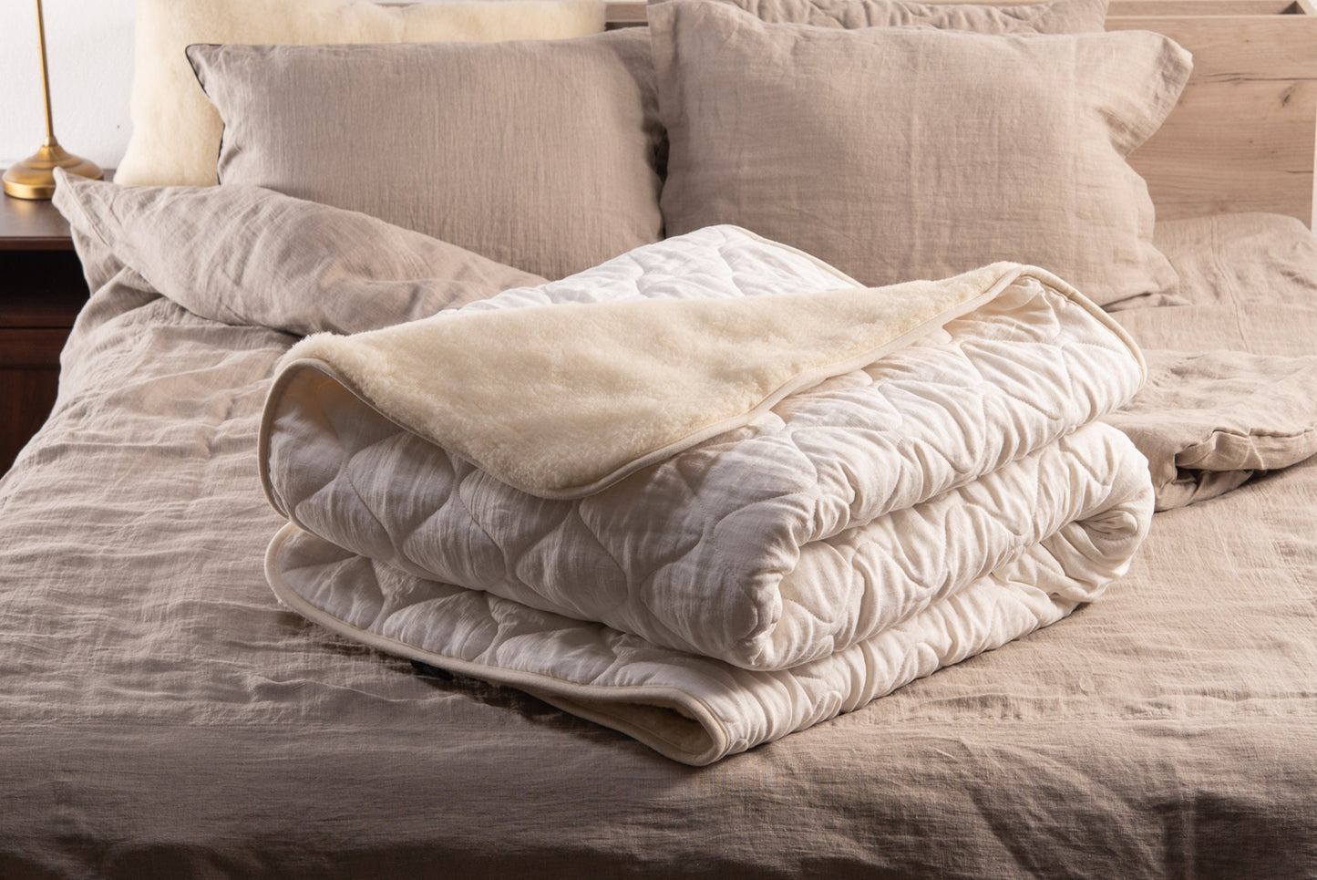 White linen and merino wool blanket folded and placed over a bed 