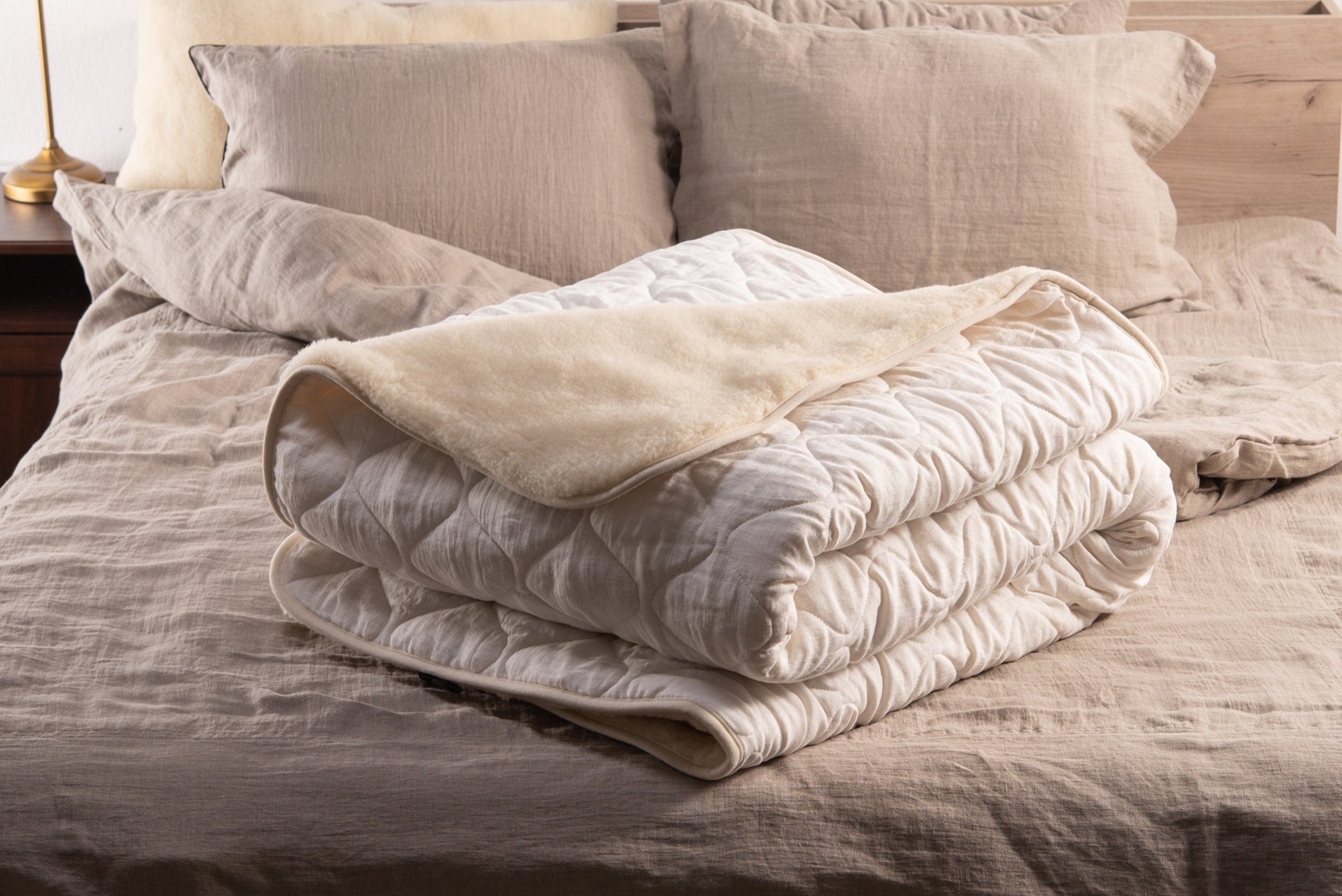 White linen and merino wool blanket folded and placed over a bed 