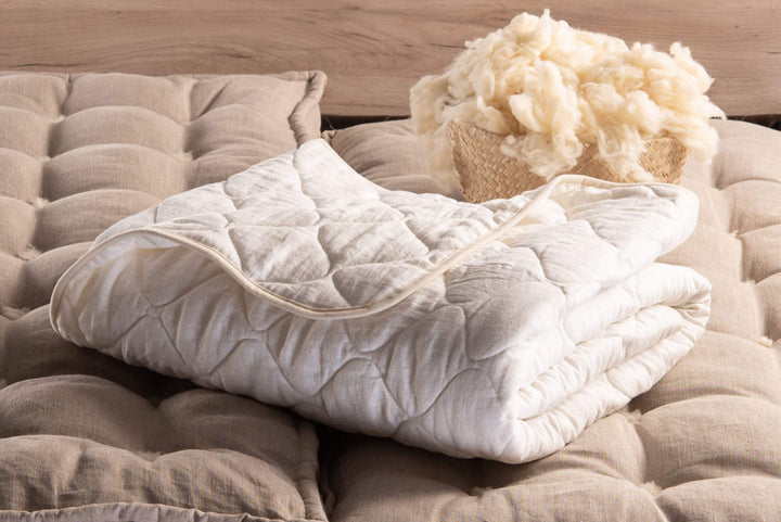 Folded wool stuffed comforter with white soft natural linen surface 