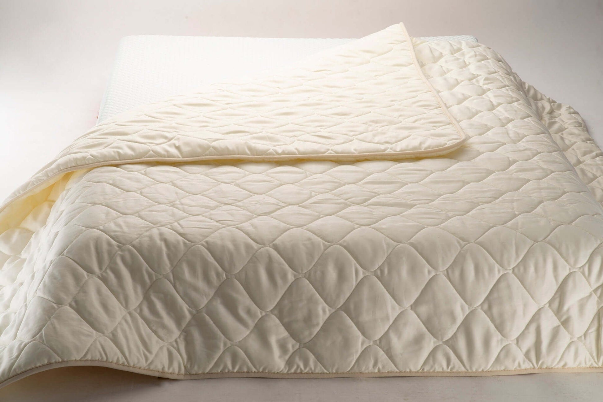Wool and cotton sateen quilt on a bed. Handmade by Woolland