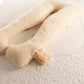 A beige, u-shaped full body merino wool pillow on a bed, designed for pregnancy support. Handmade by the Woolland